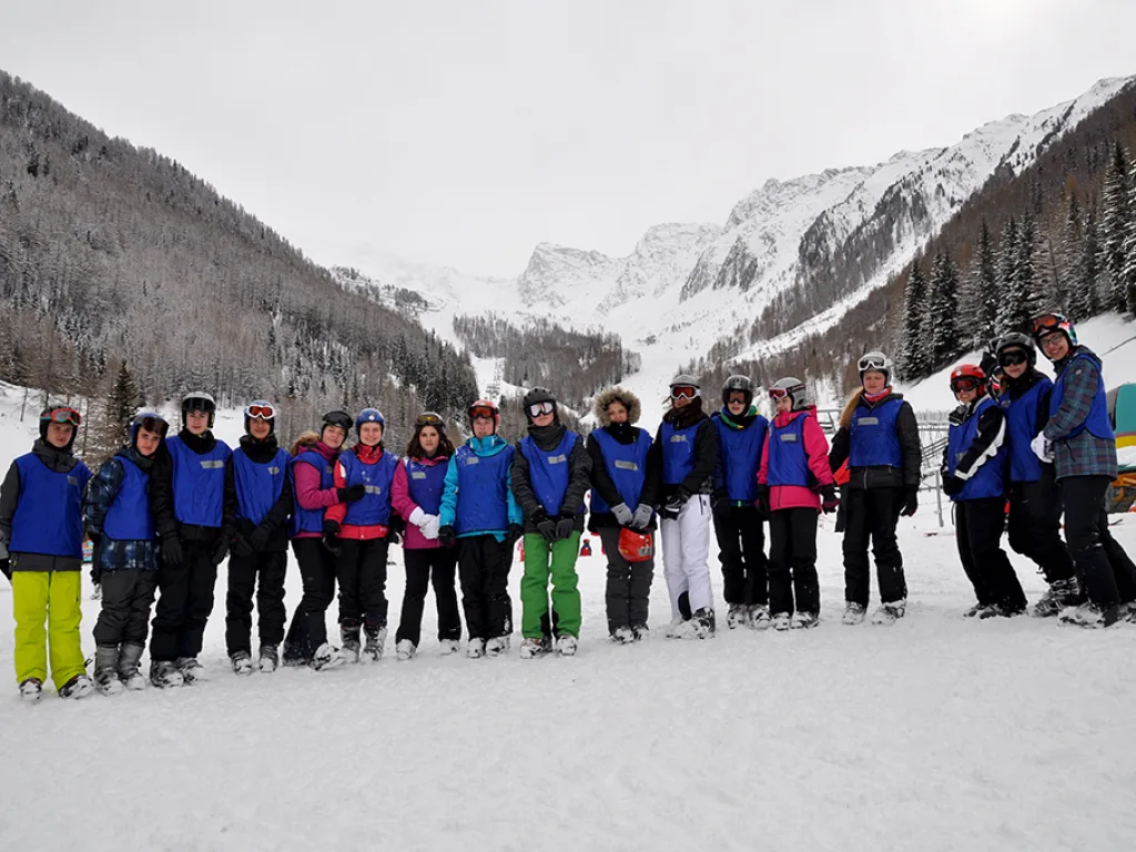 Große Gruppe steht in einer Reihe auf der Piste vor dem Tal.